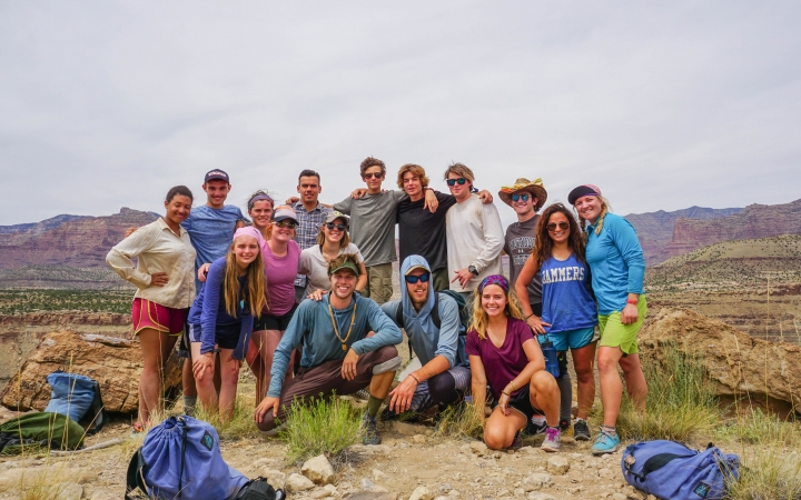 A group of people smile for a photo in a desert landscape.